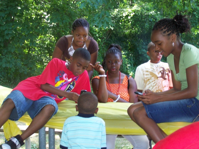 A group of young people entertaining themselves playing cards during the Saturday picnic.